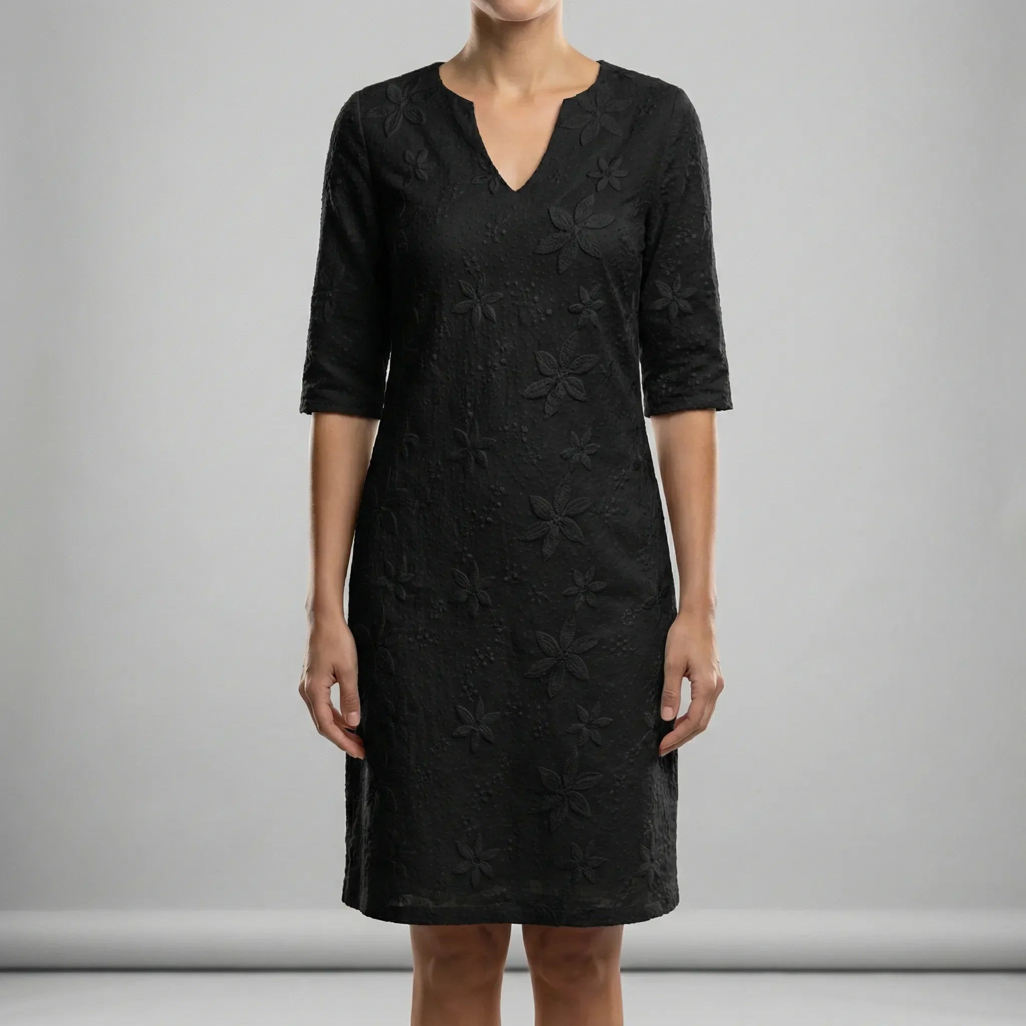 Black lace dress worn by a person on a gray background