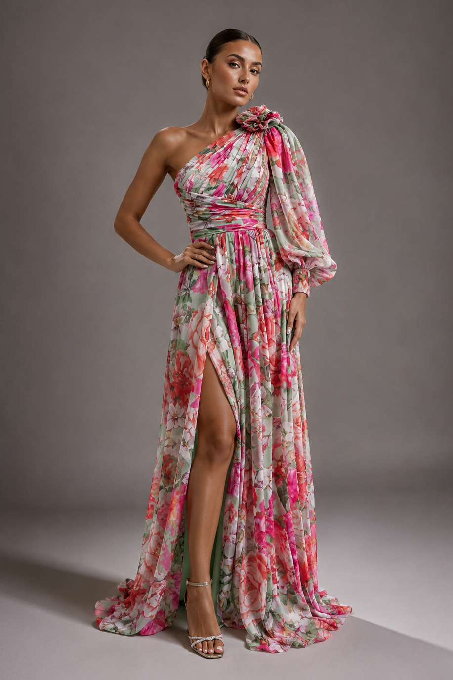 Woman wearing a floral one-shoulder dress with a slit on a gray background