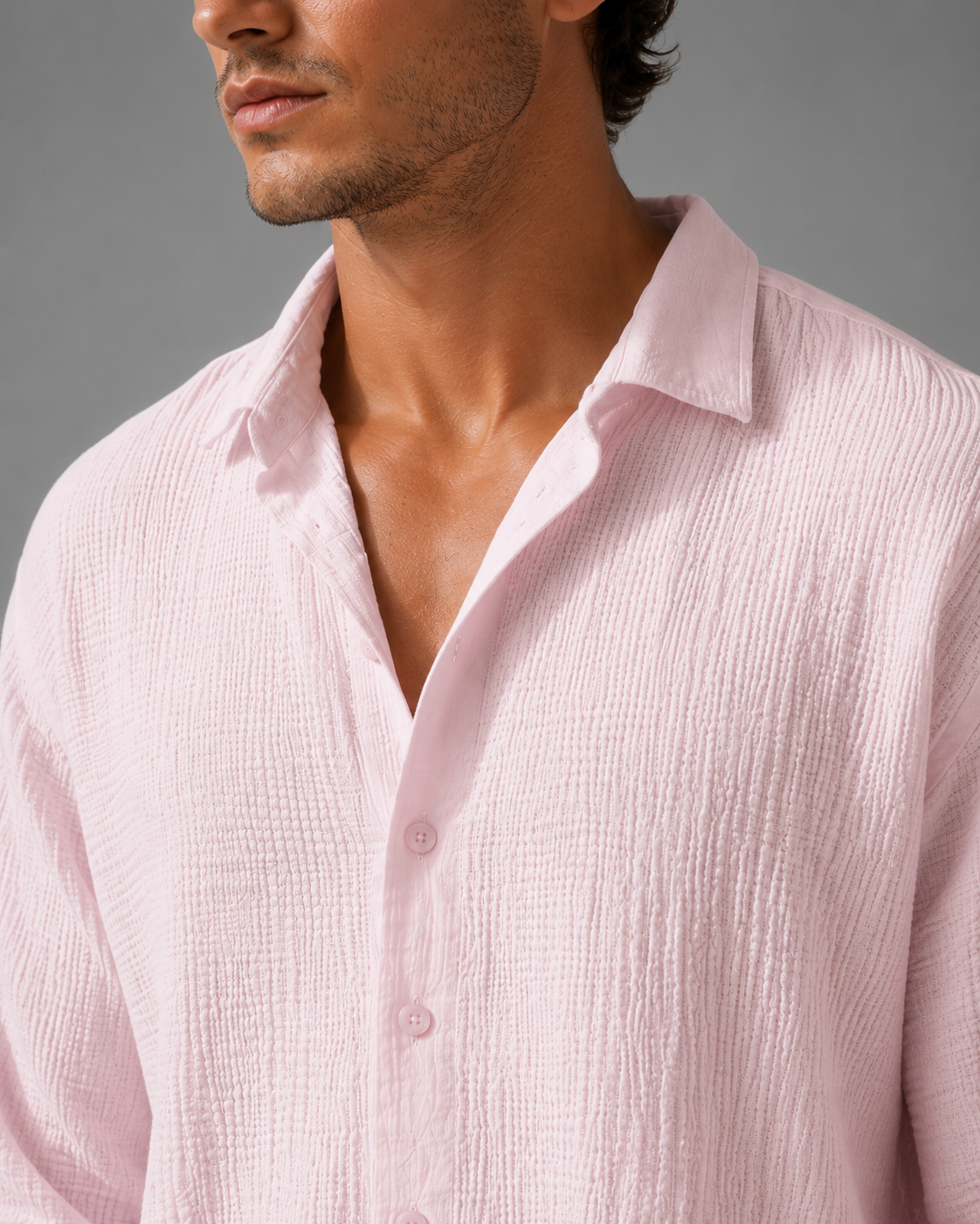 Close-up of a man wearing a light pink textured shirt against a gray background