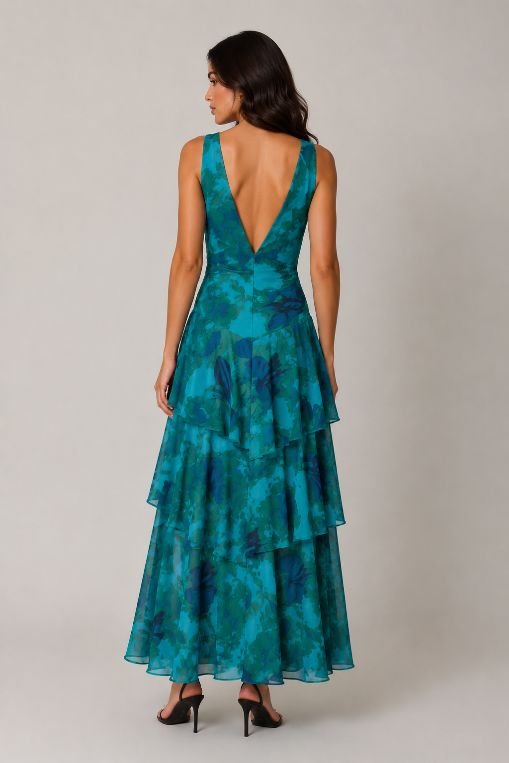 Woman wearing a teal and blue patterned dress with a plain background