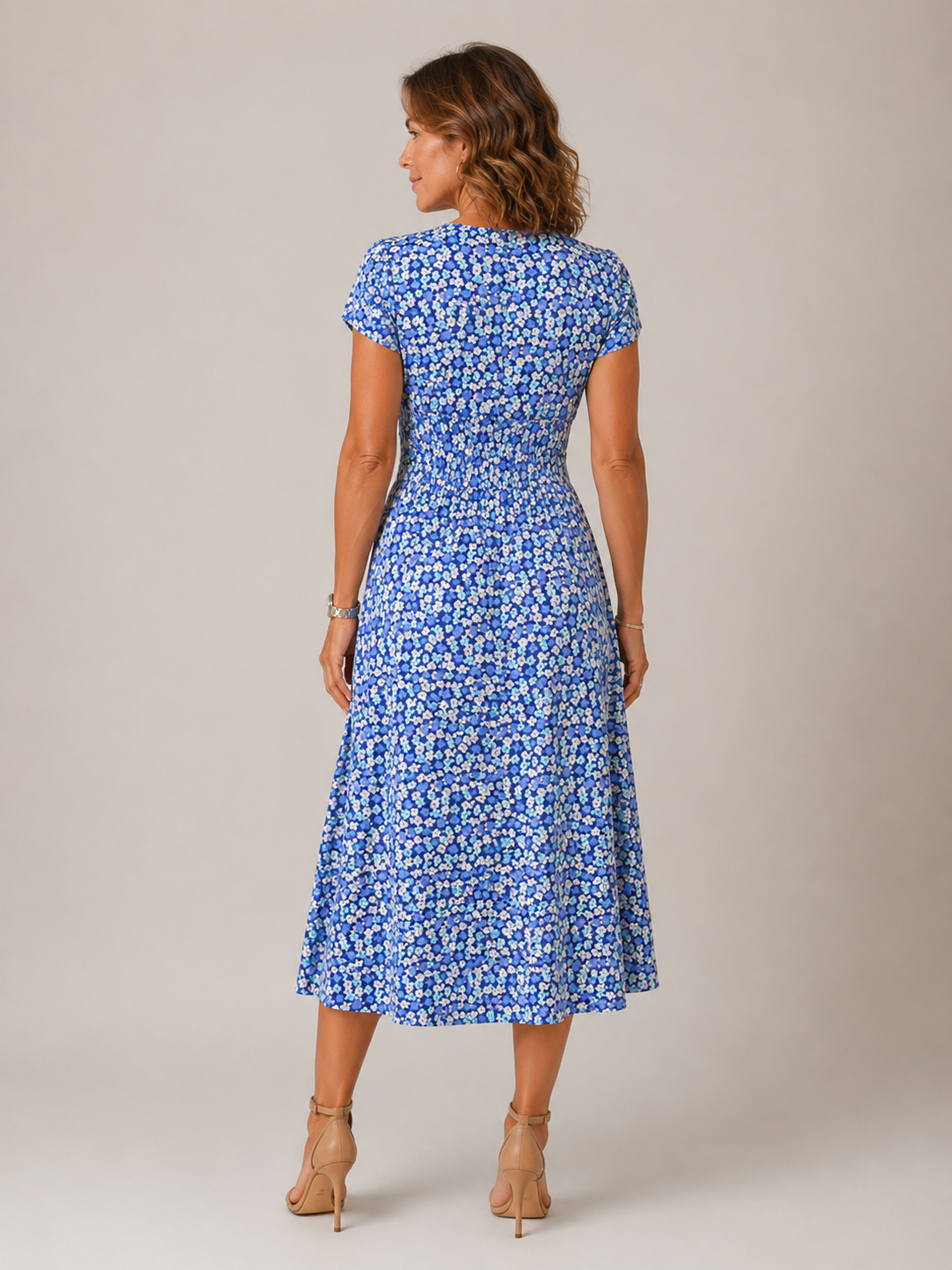 Woman wearing a blue floral dress against a plain background