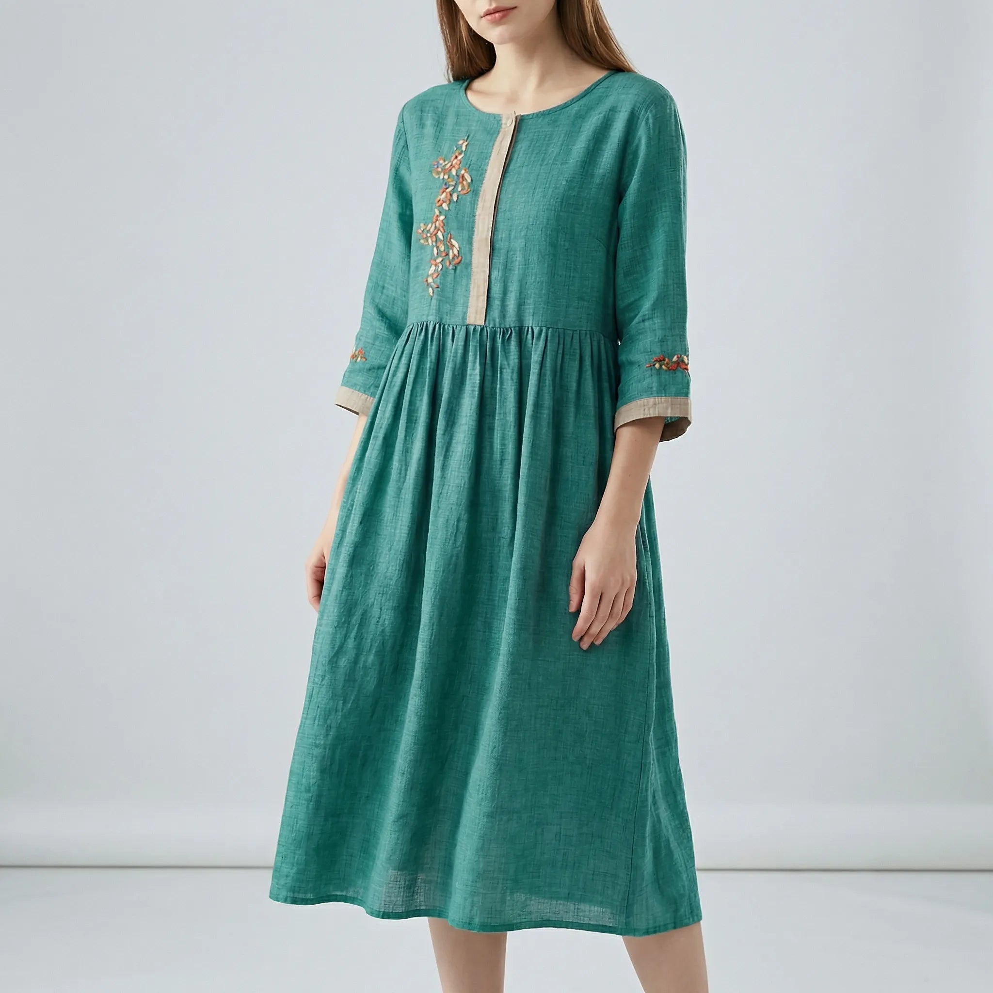 Teal dress with embroidery on a plain background