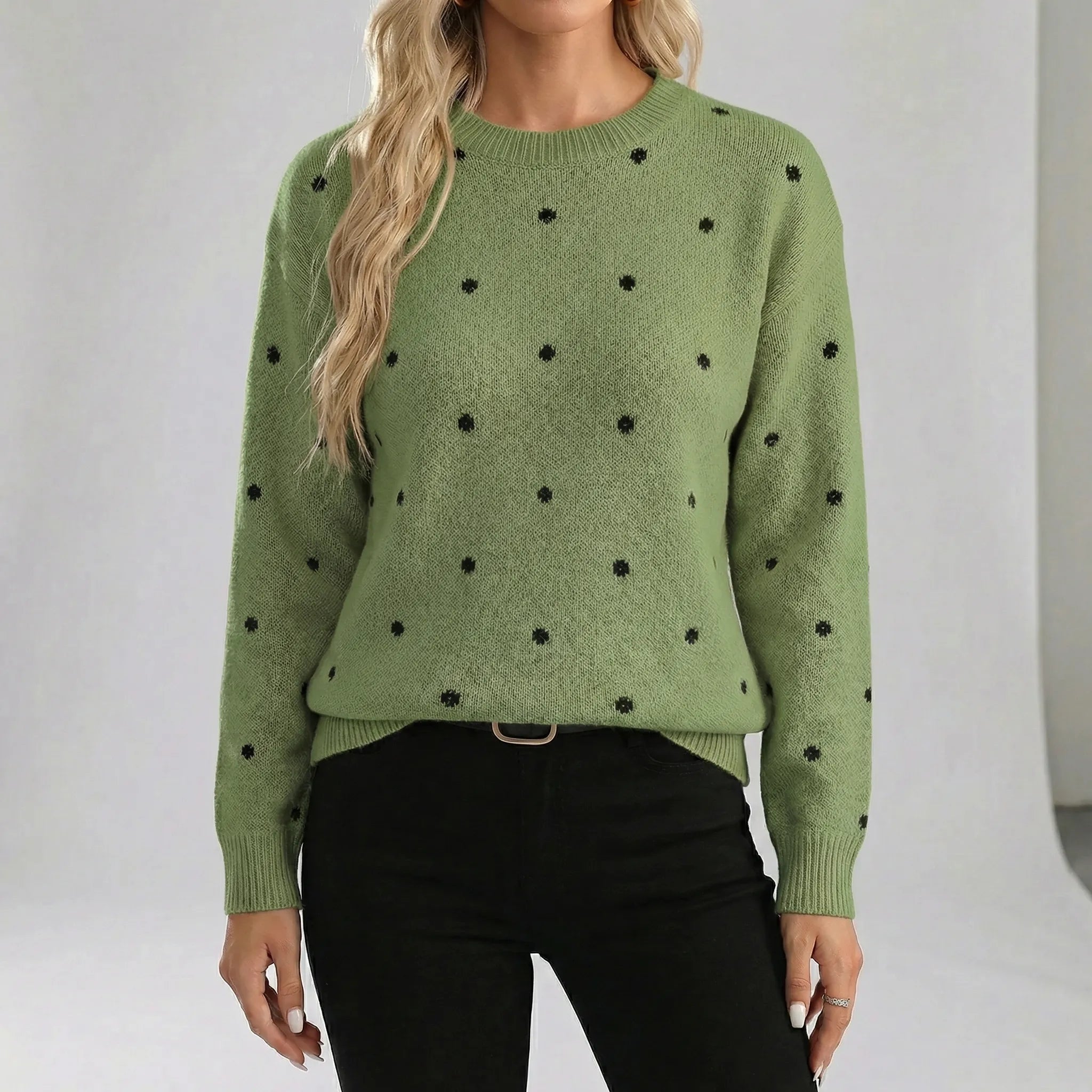 Green sweater with black polka dots worn by a person on a white background