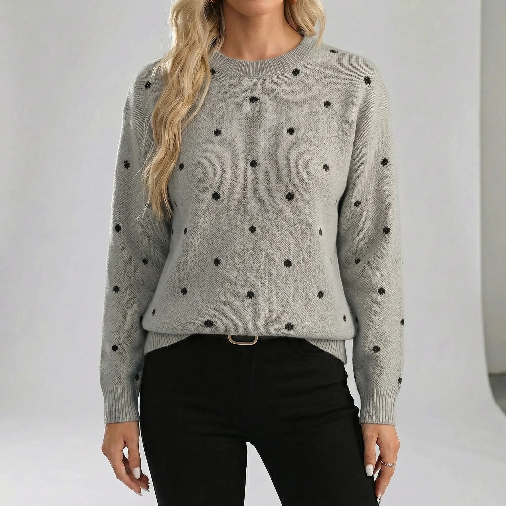 Person wearing a gray sweater with black polka dots against a plain background