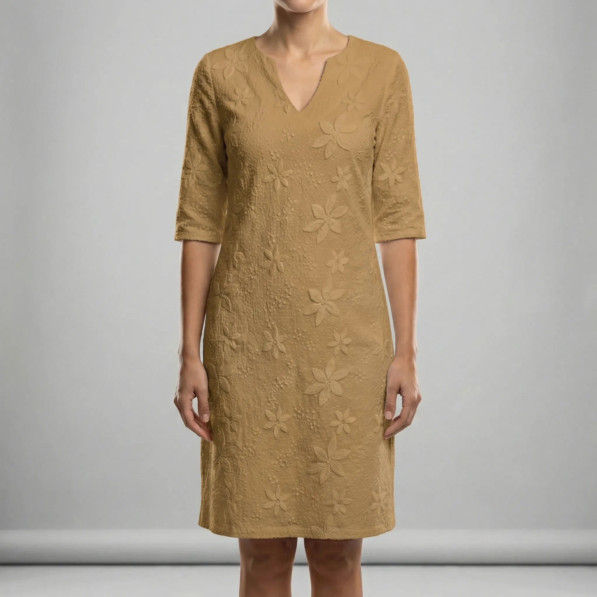 Woman wearing a beige dress with floral patterns on a gray background