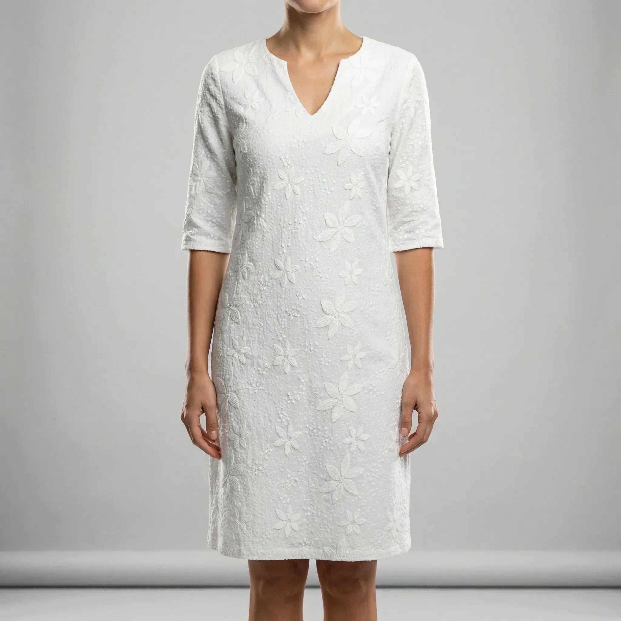White dress with floral pattern worn by a person on a gray background