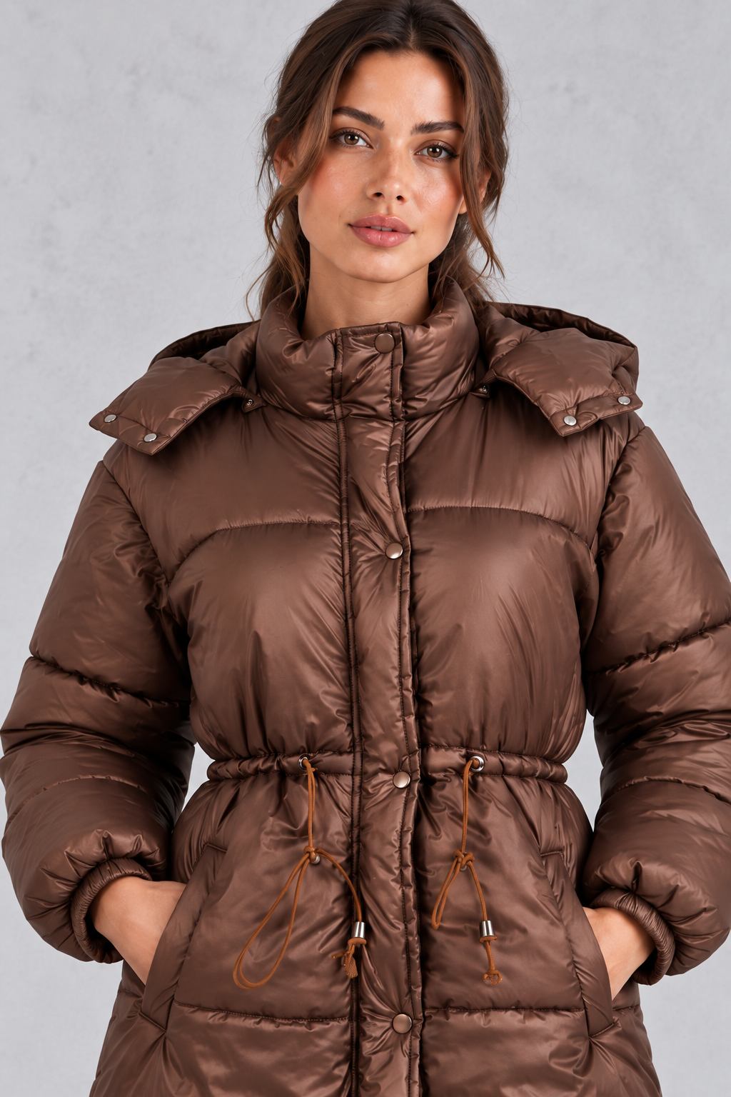 Women’s longline hooded puffer coat with quilted padding, a high neckline, adjustable drawstring waist and practical side pockets.