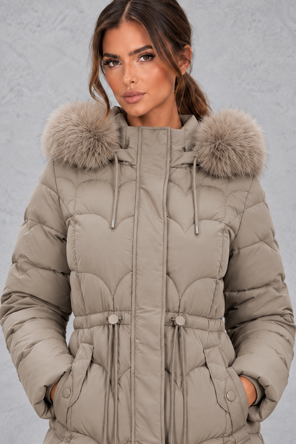 Women’s longline quilted puffer coat with a detachable faux fur hood, adjustable drawstring waist and warm padded construction.