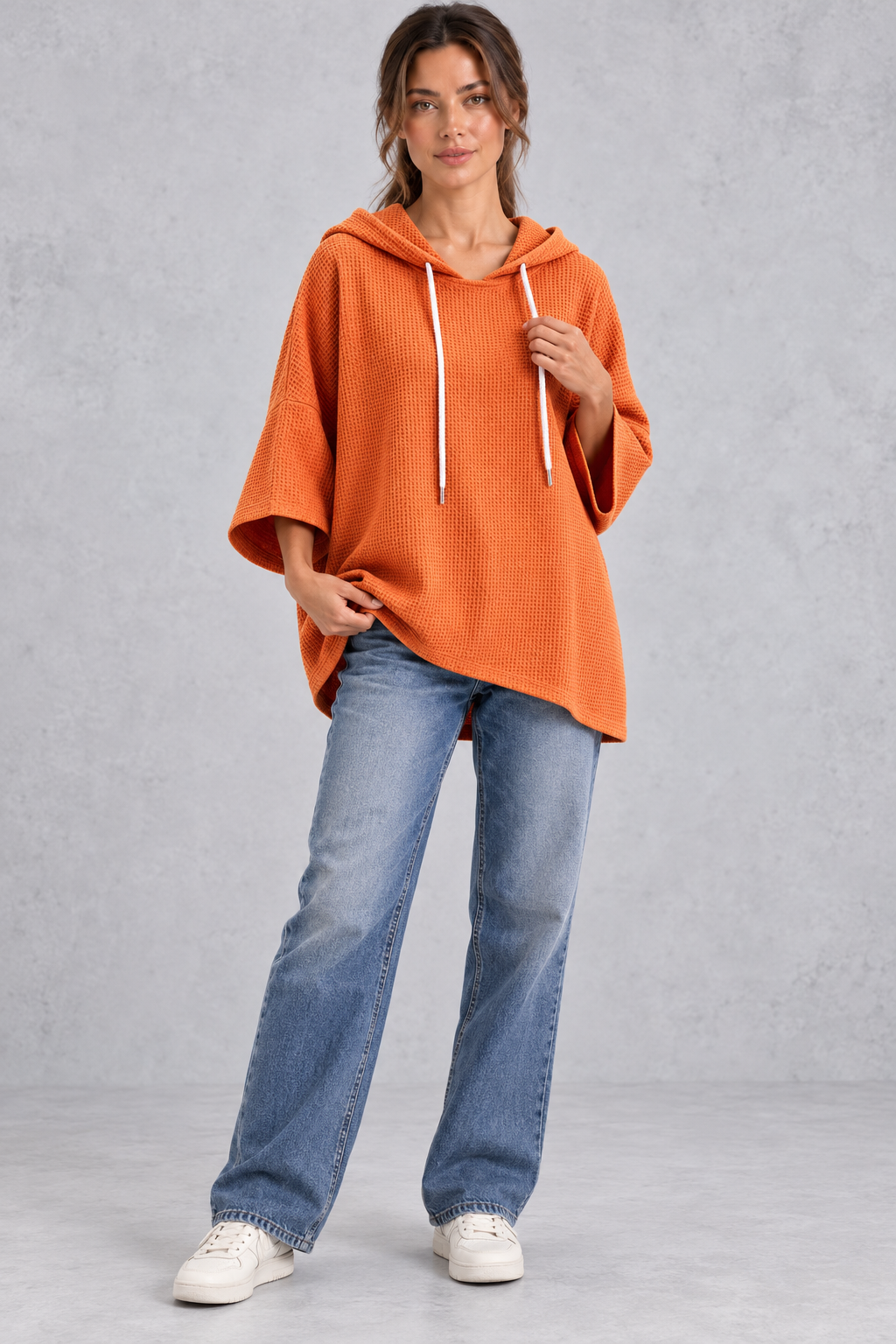 Women's plus size orange waffle knit oversized hooded jumper styled with jeans – full-length front view