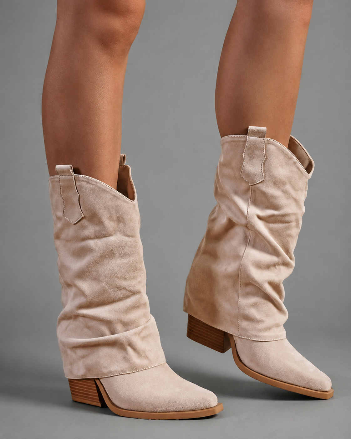 Women’s pointed toe knee high boots with a low chunky heel and relaxed Western-inspired shaft in a neutral shade.