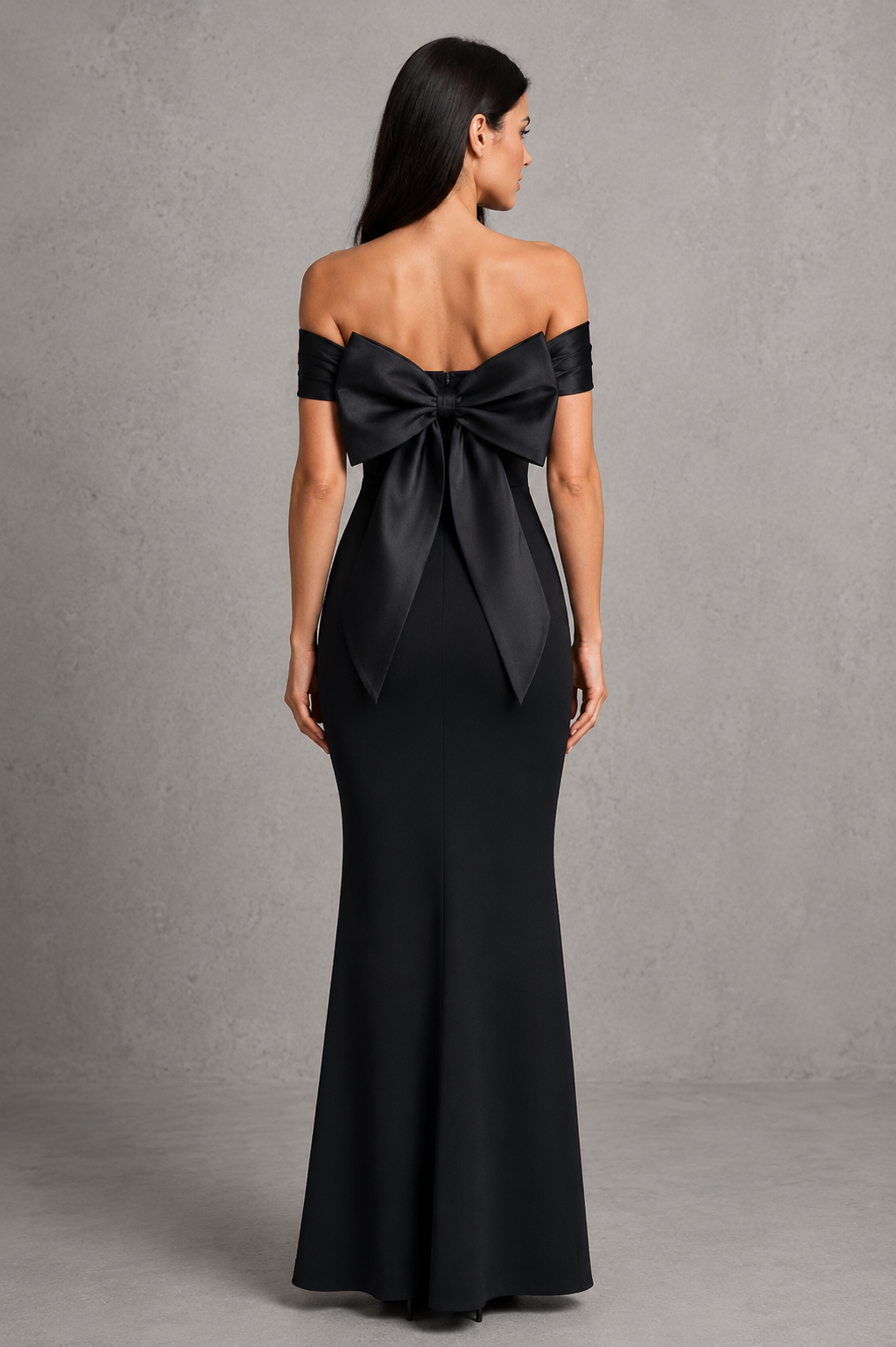 Woman wearing a black off-shoulder gown with a large bow detail on a gray background