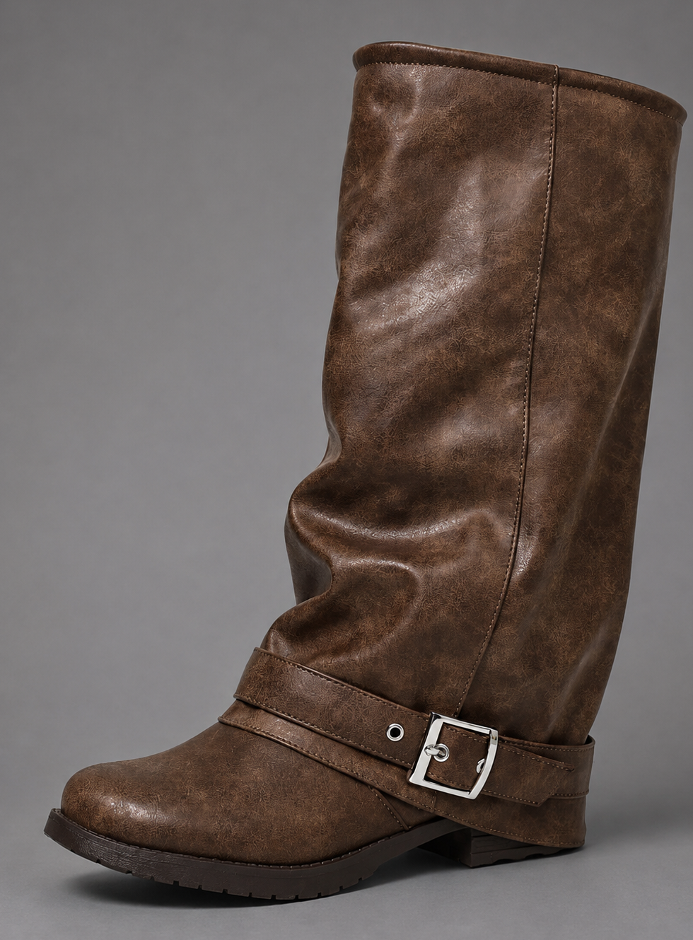 Women’s black slouchy knee-high boots with buckle strap, round toe, low block heel and chunky lug-tread sole.