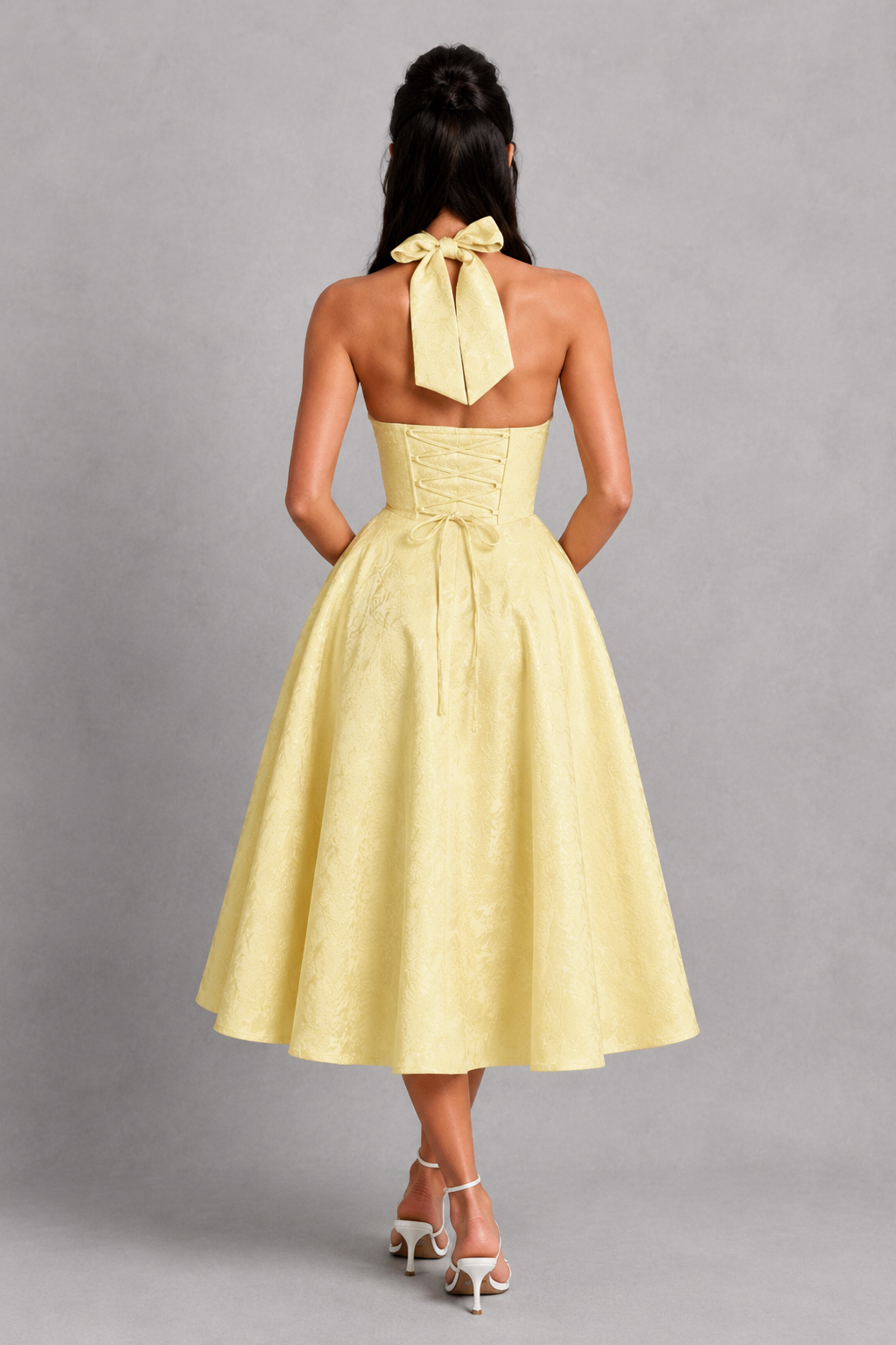 Yellow dress with a bow detail on a gray background