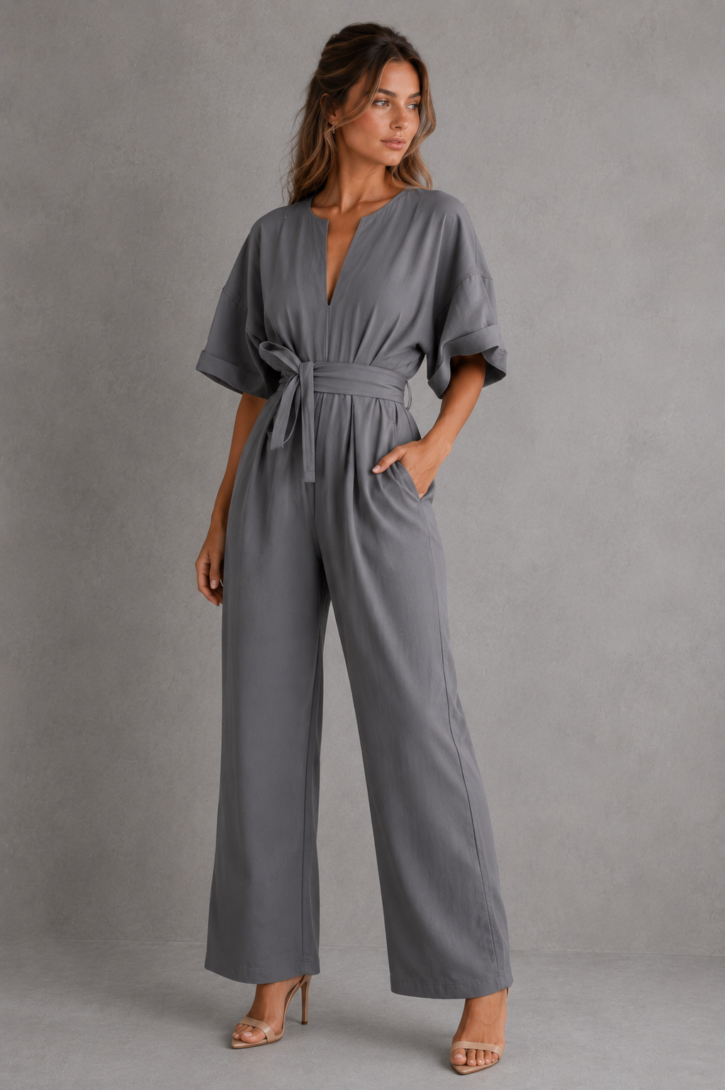 Woman wearing a gray jumpsuit against a plain background