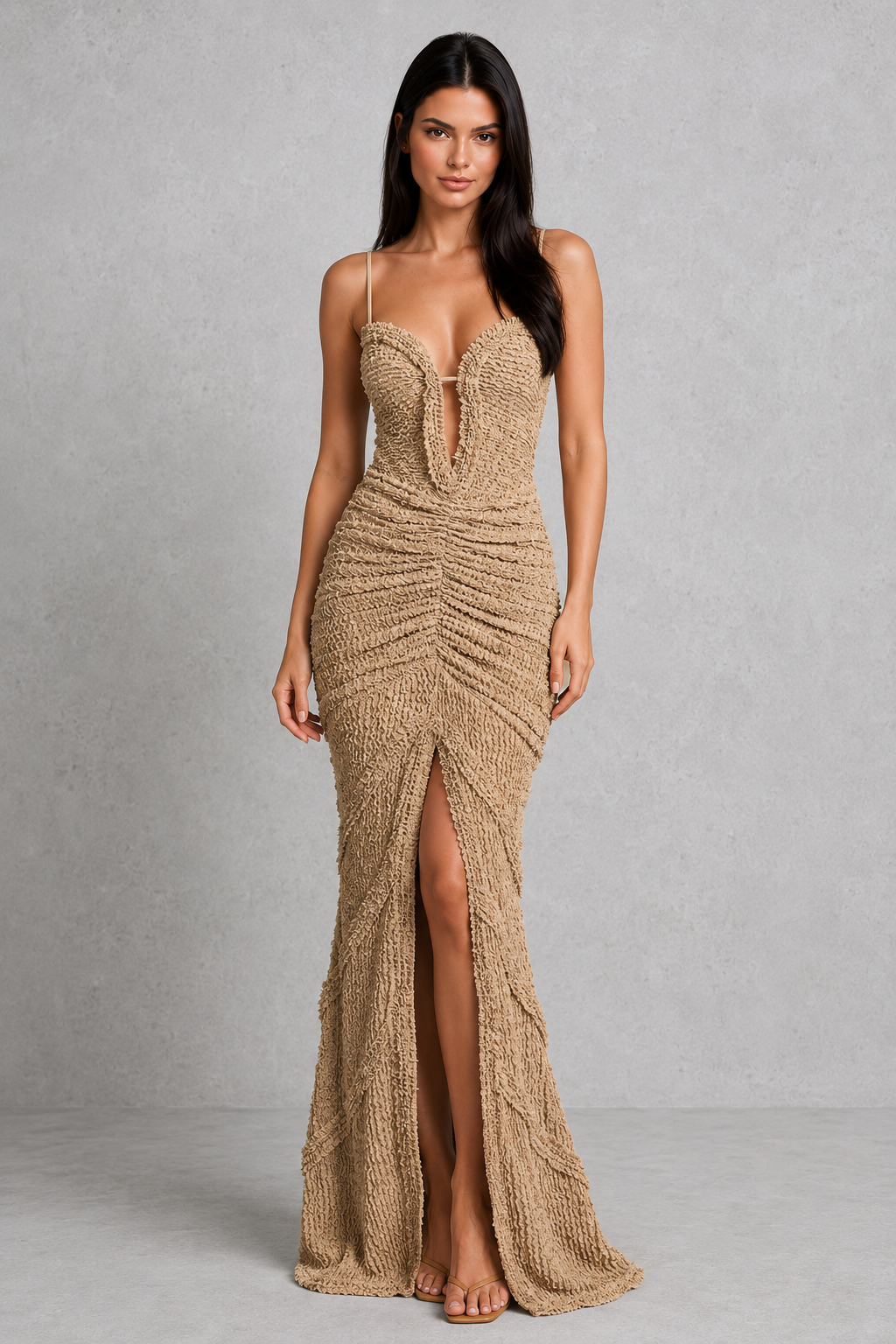 Woman wearing a beige evening gown with a slit on a gray background