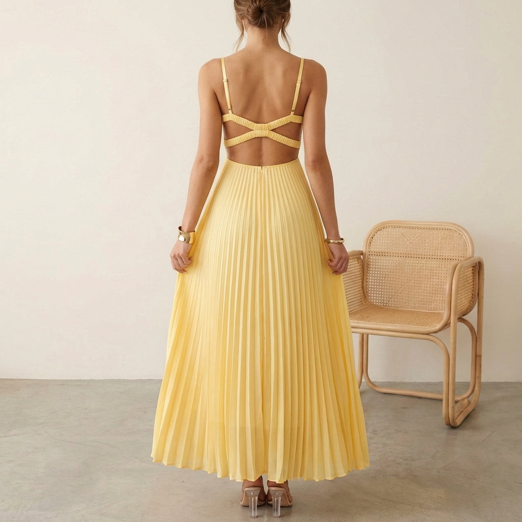 Woman wearing a yellow pleated dress with a chair in the background