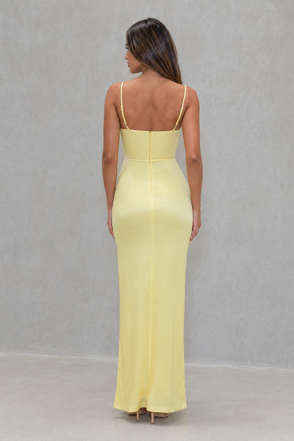 Woman wearing a light yellow evening gown against a gray background
