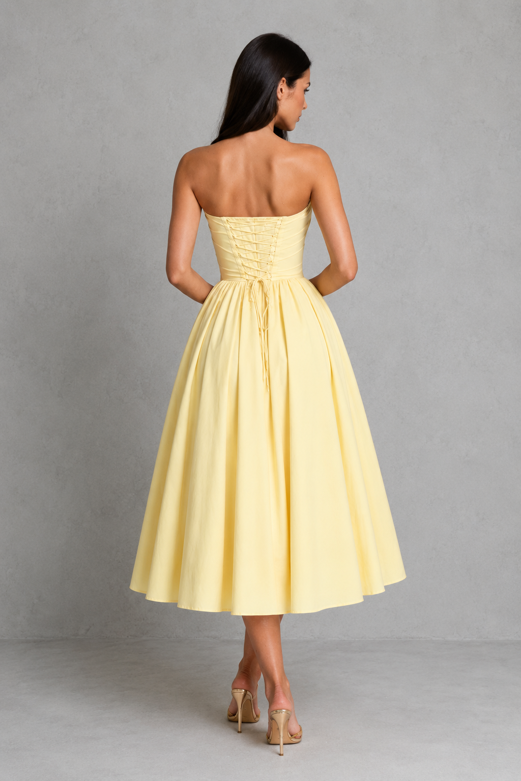 Woman wearing a yellow strapless dress against a gray background
