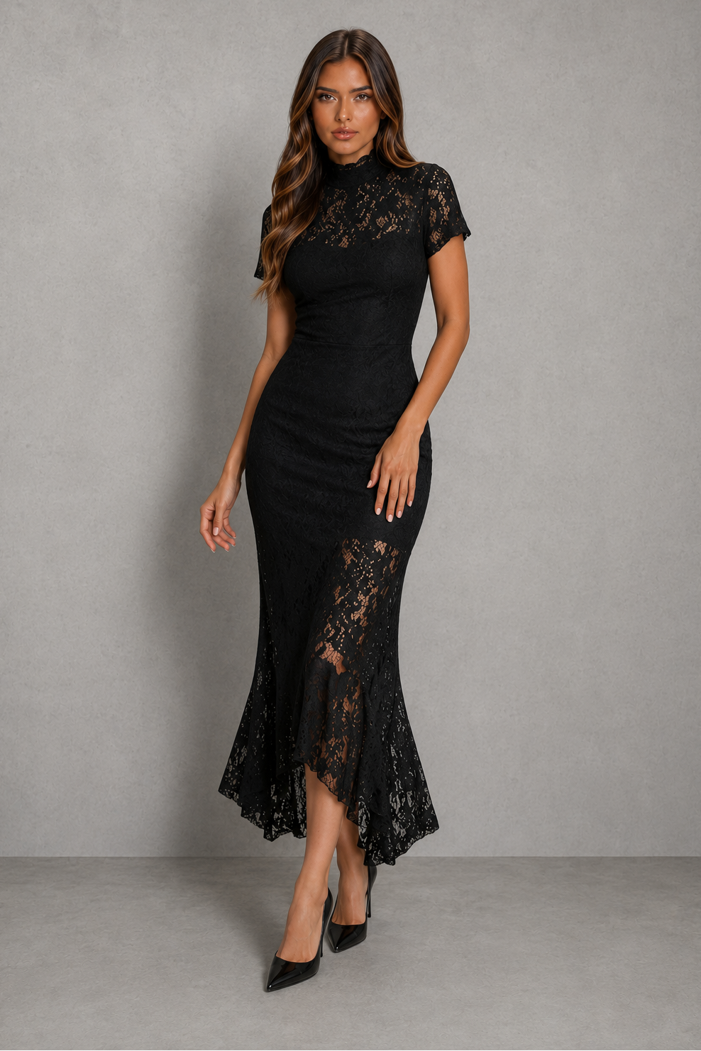 A woman modeling a black lace midi dress with short sleeves, a high mock neck, and a flared ruffled hem, standing against a textured gray studio background.