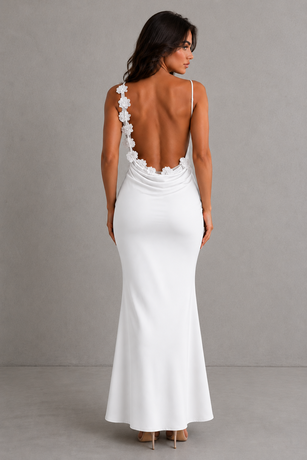 Woman wearing a white evening gown with floral back design against a gray background