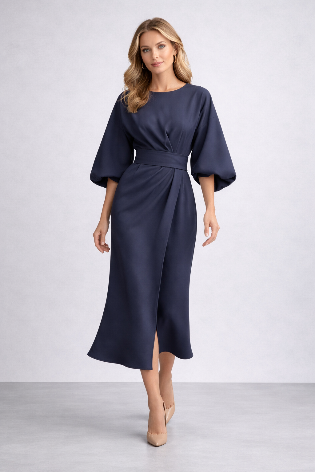 Woman wearing a navy blue dress with wide sleeves on a white background