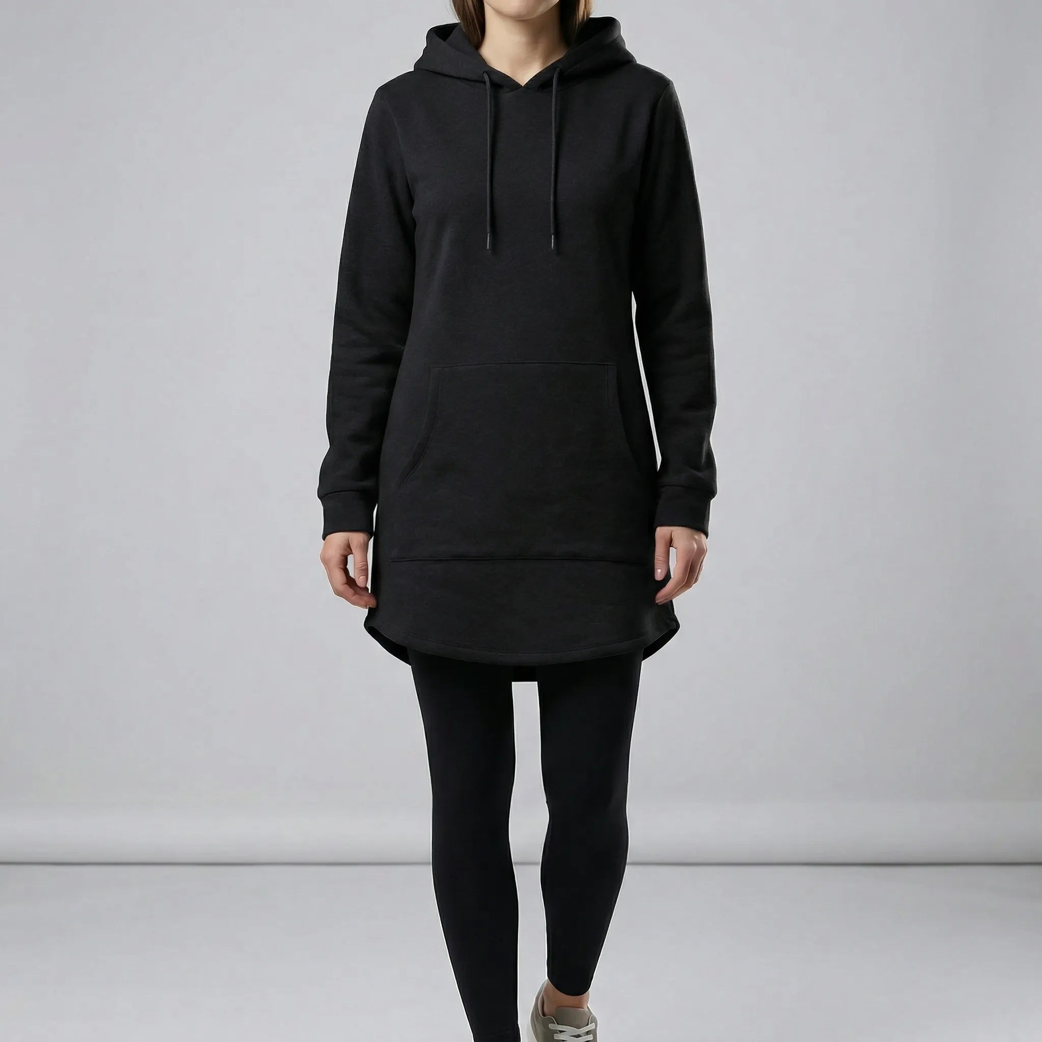 Person wearing a black hoodie and leggings on a plain background