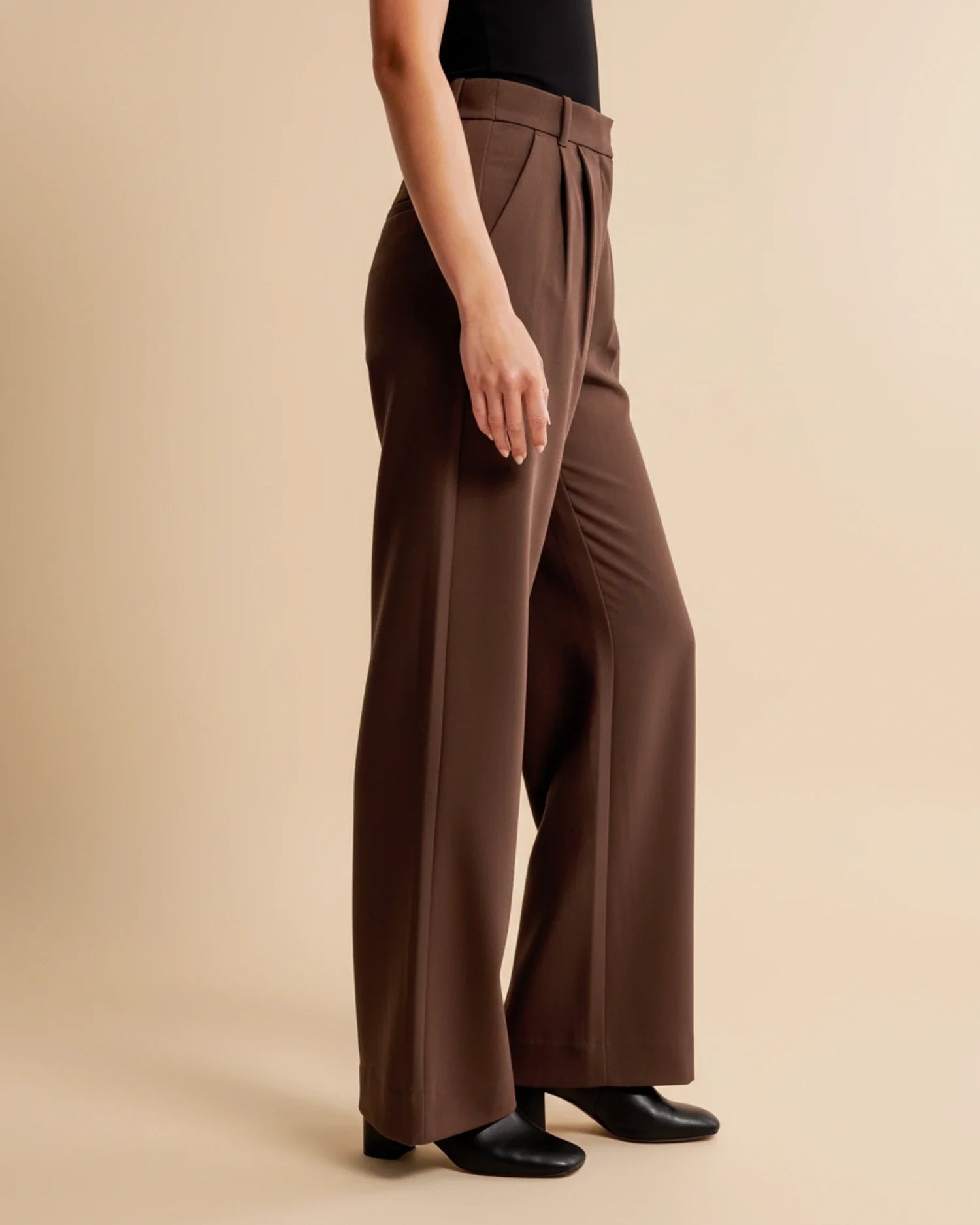 Brown wide-leg pants worn by a person on a beige background
