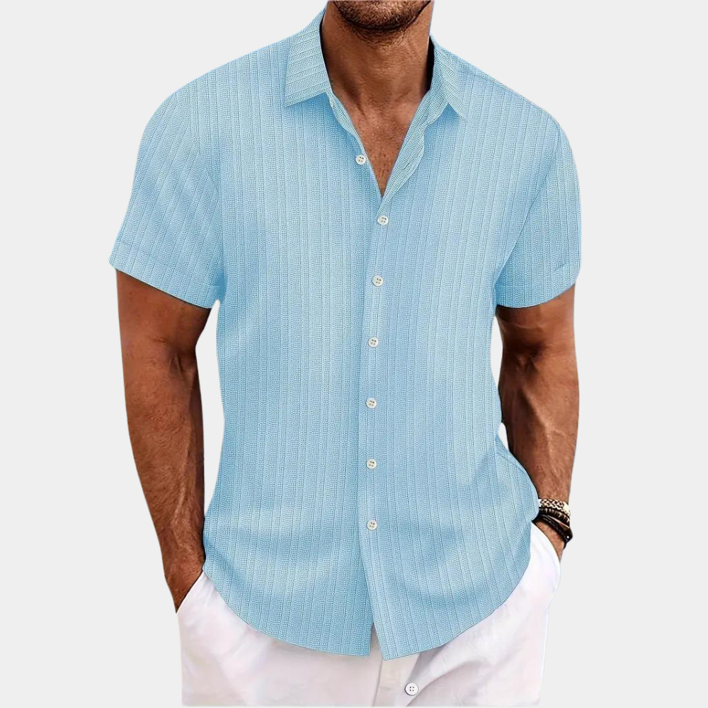 Man wearing a light blue striped shirt with white pants on a plain background