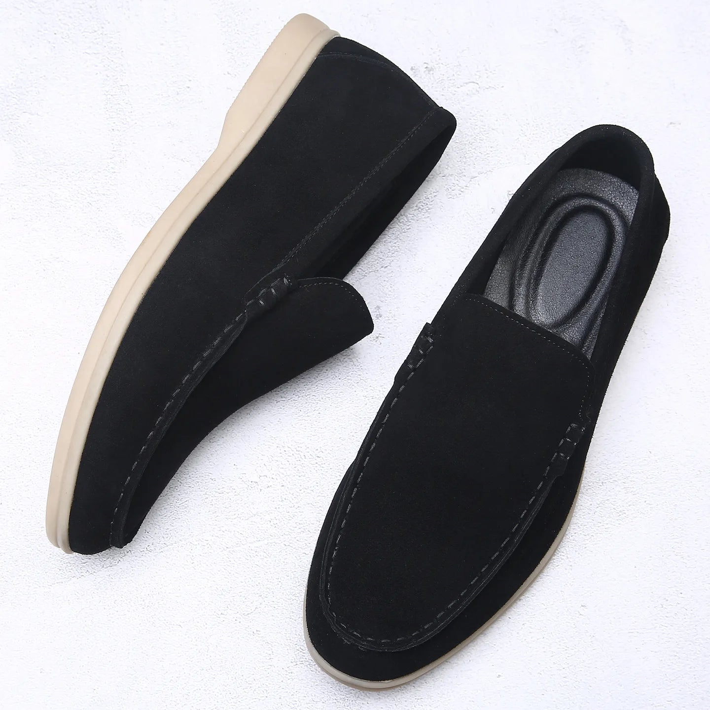 Black loafers with beige soles on a white background
