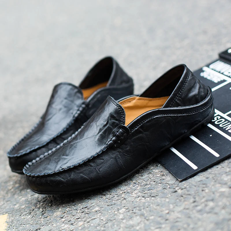 Black leather loafers on a gray surface with a black mat underneath
