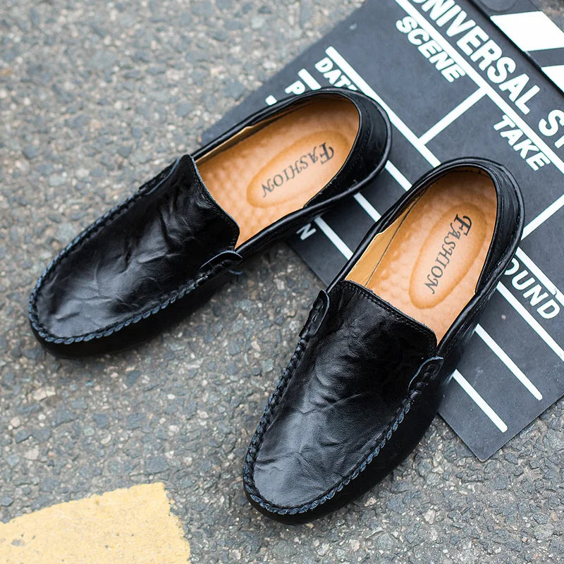 Black leather loafers on a black film slate background