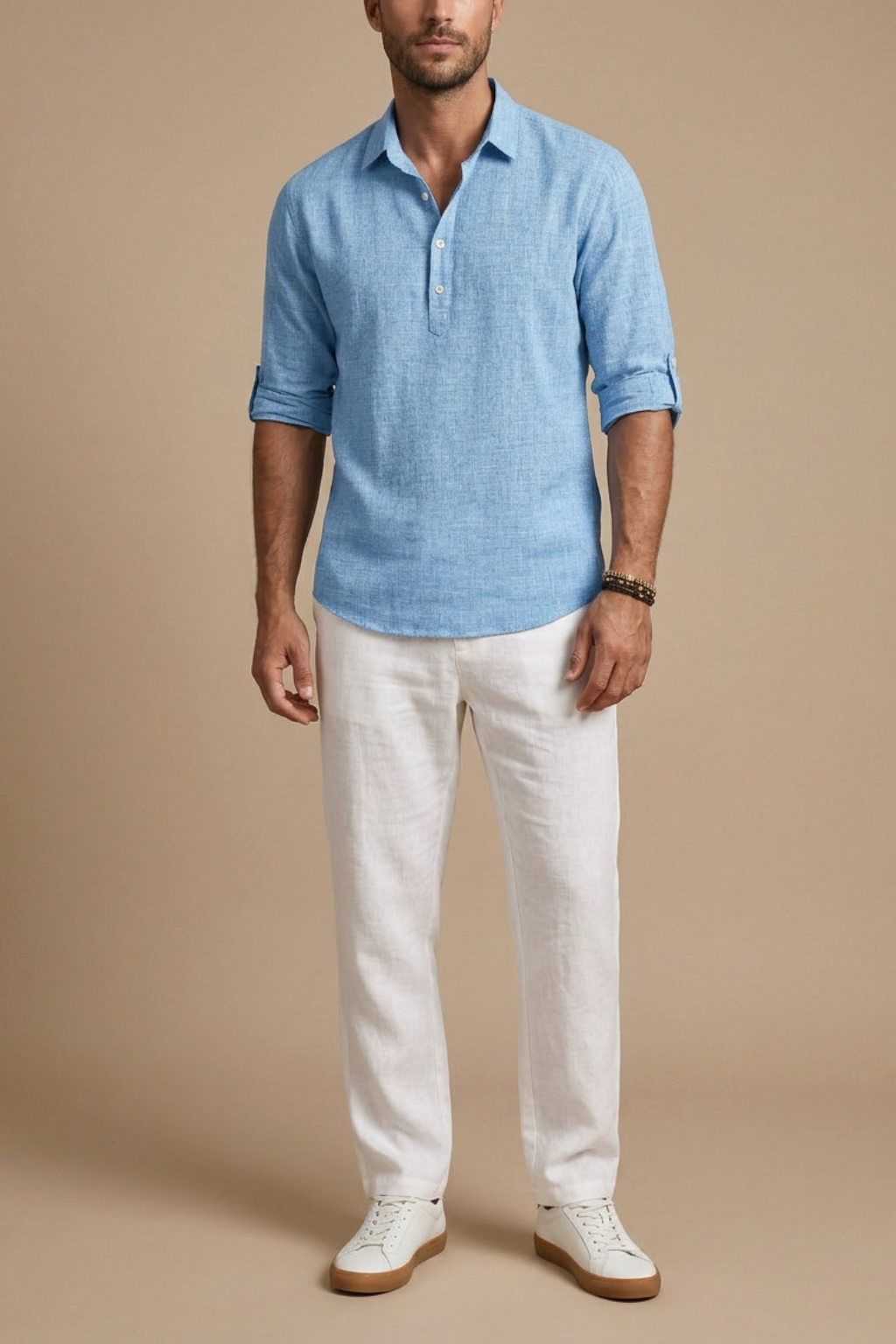 Man wearing a blue linen shirt and white pants against a beige background