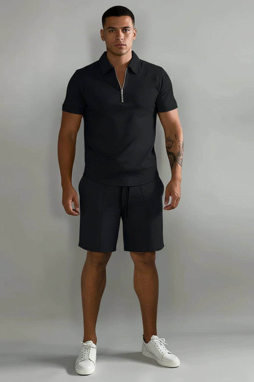 Person wearing a black polo shirt and shorts with white sneakers on a gray background