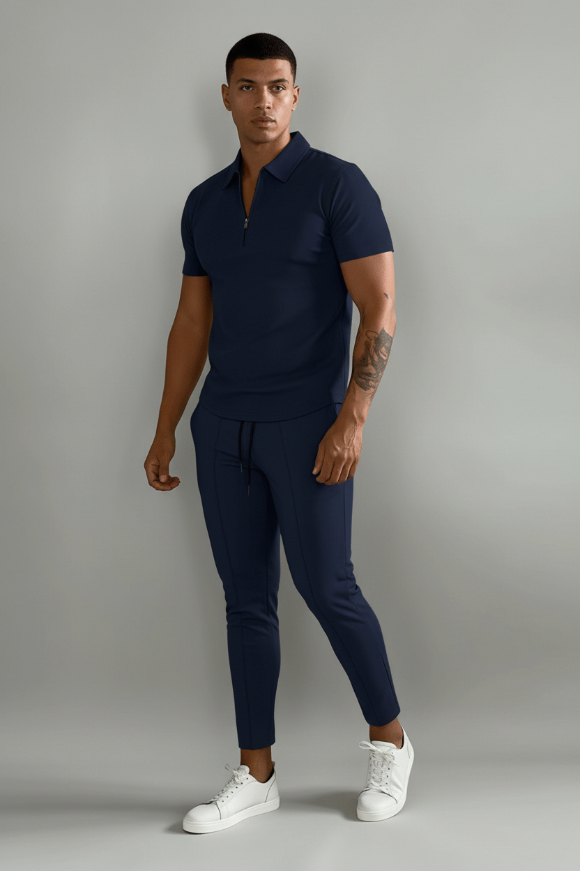 Person wearing a navy blue polo shirt and pants with white sneakers on a plain background