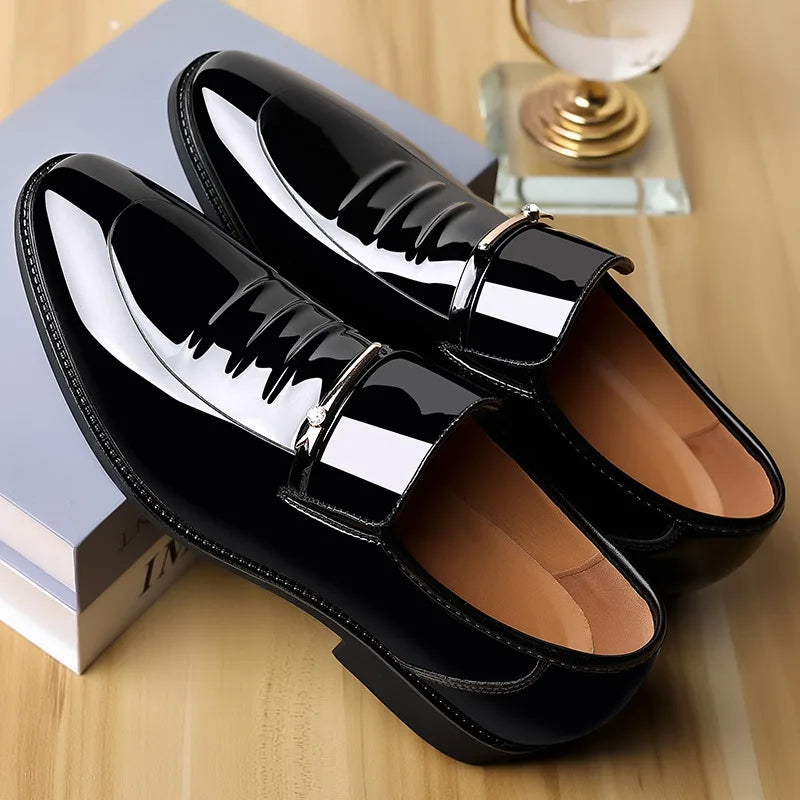 Black patent leather shoes with gold buckles on a wooden surface