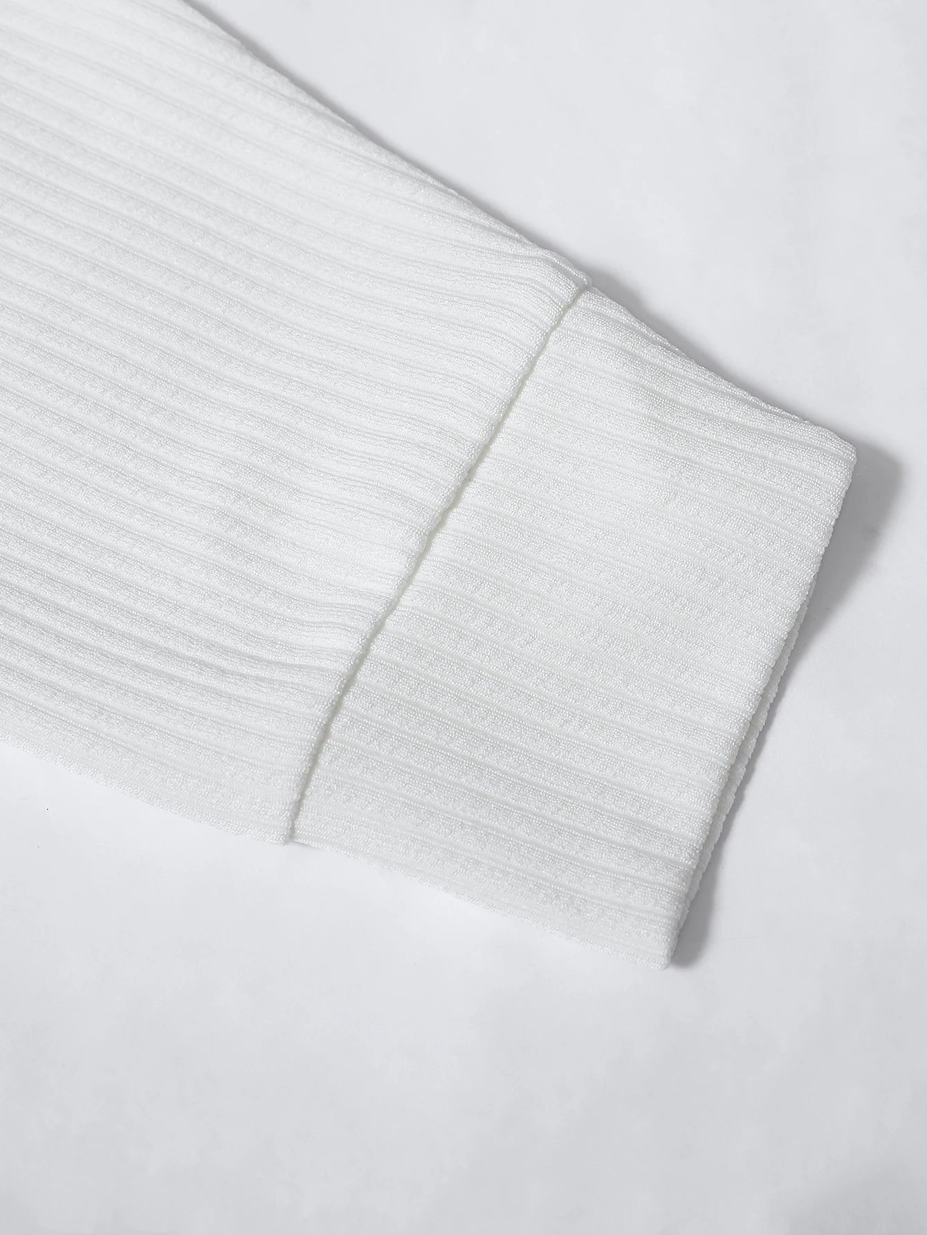 Close-up of a light gray ribbed sweater sleeve on a white background