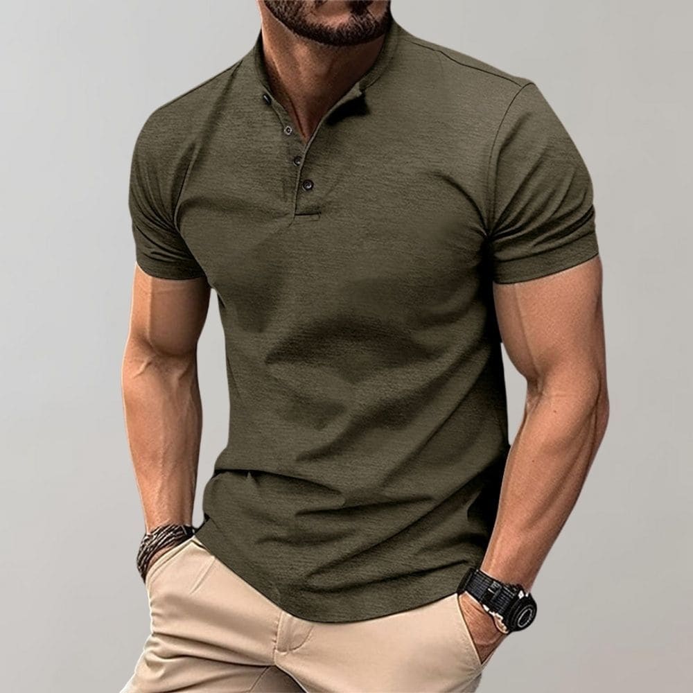 Man wearing an olive green polo shirt and beige pants against a gray background