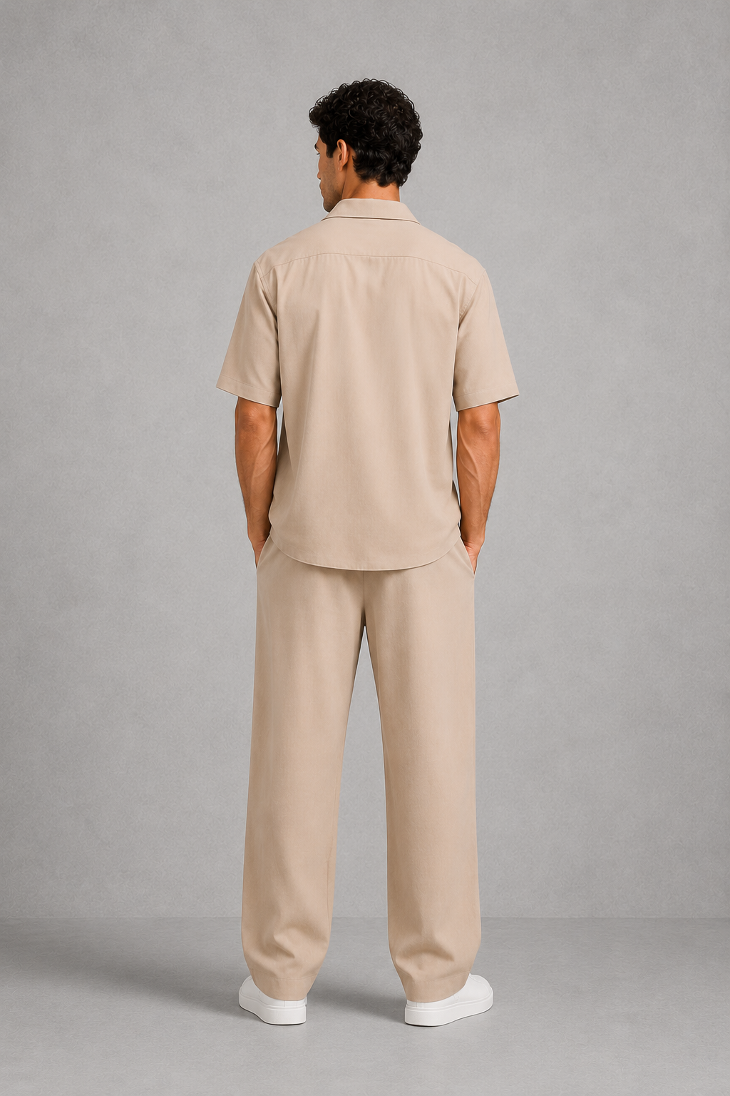Man wearing a beige outfit standing against a gray background