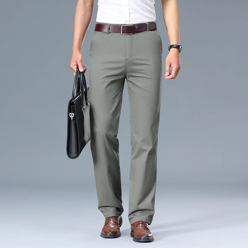 Person wearing olive green pants with a white shirt and brown shoes on a gray background