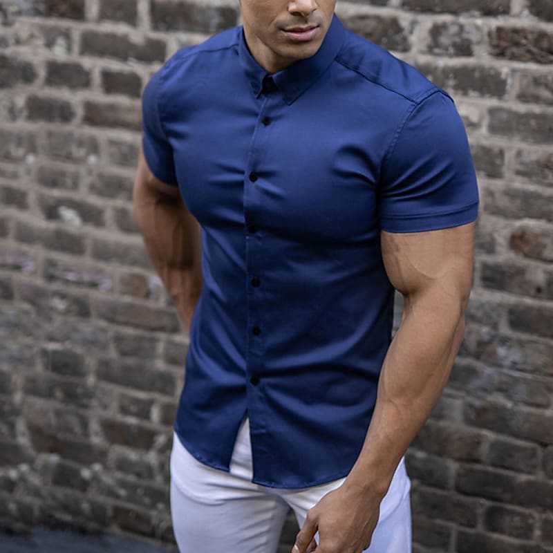 Man wearing a blue short-sleeve shirt against a brick wall