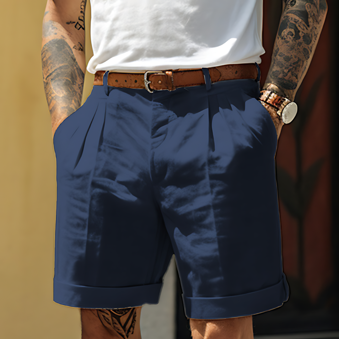 Person wearing navy shorts with a white shirt and brown belt against a blurred background