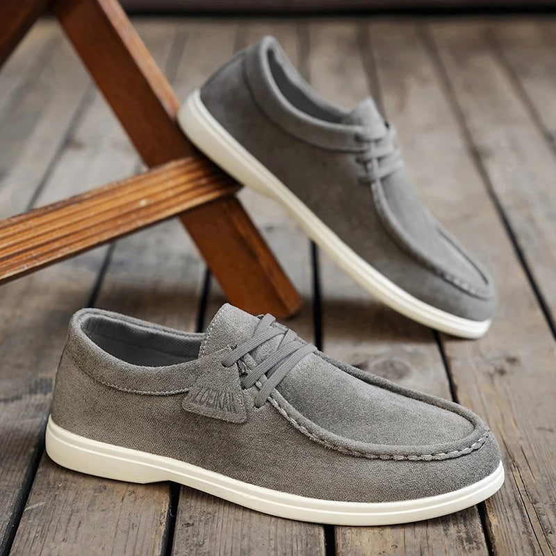 Gray suede shoes with white soles on a wooden floor
