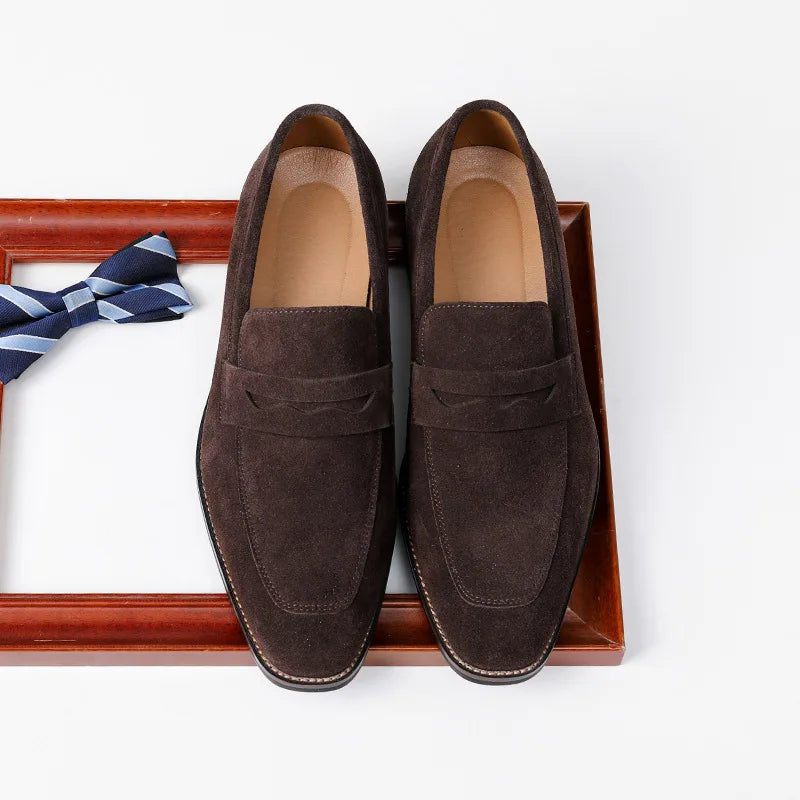 Pair of brown suede loafers on a white background with a striped tie.