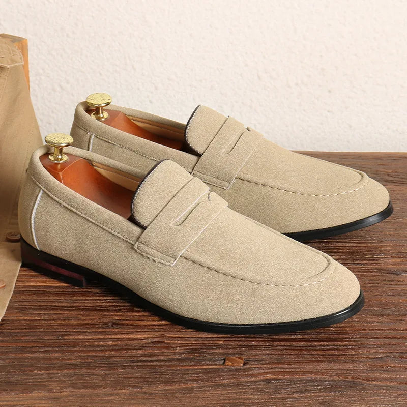 Pair of beige loafers on a wooden surface with a neutral background