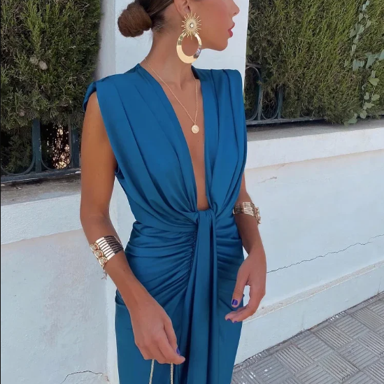 Woman wearing a blue dress with gold accessories outdoors.