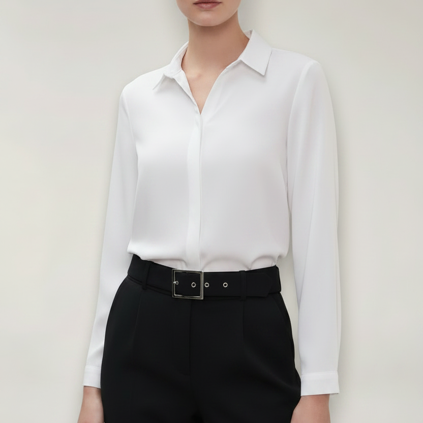 Person wearing a white shirt and black pants against a plain background
