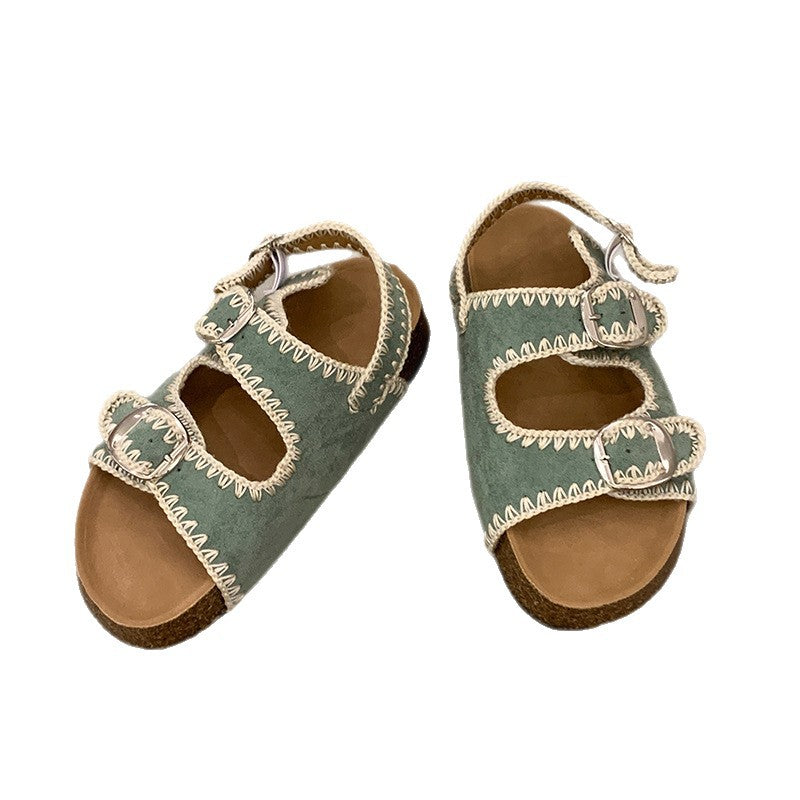 Pair of green sandals with brown soles on a white background