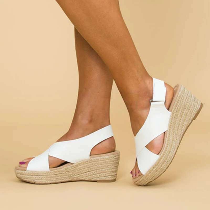 White wedge sandals with jute sole worn by a person on a beige background