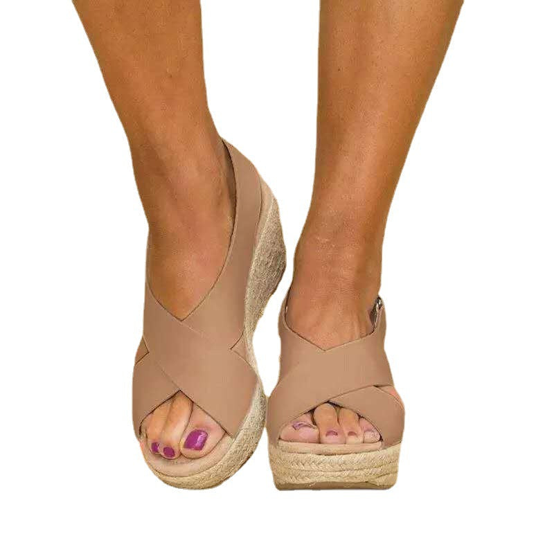 Beige wedge sandals with espadrille soles worn by a person on a white background