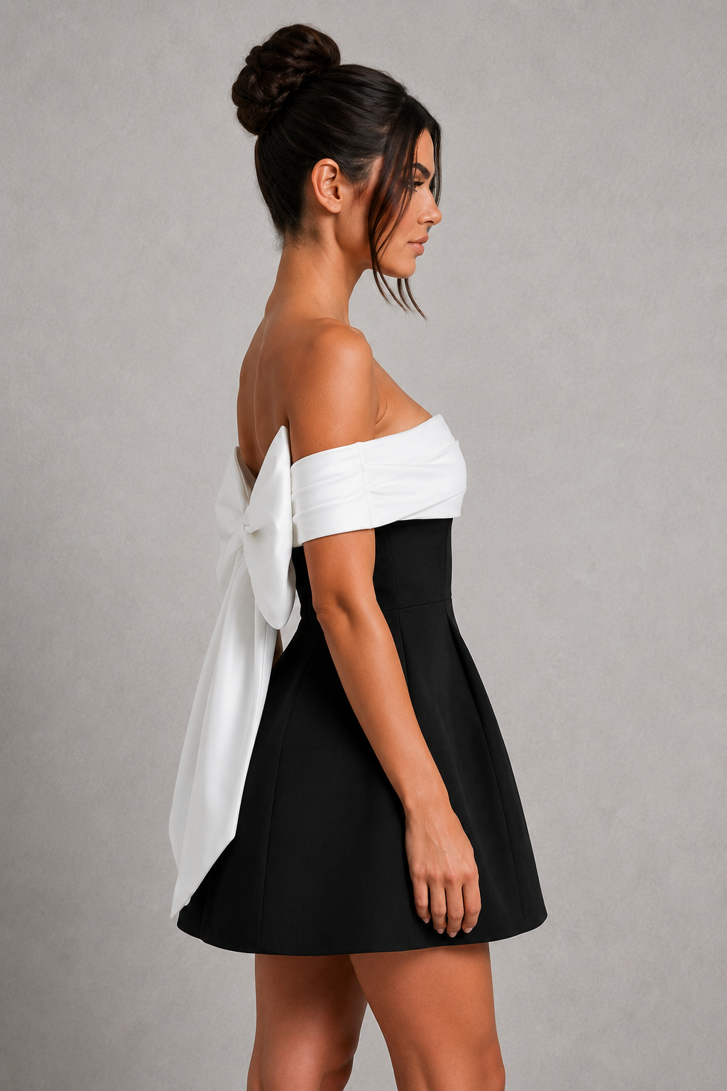 Woman wearing a black and white off-shoulder dress against a gray background